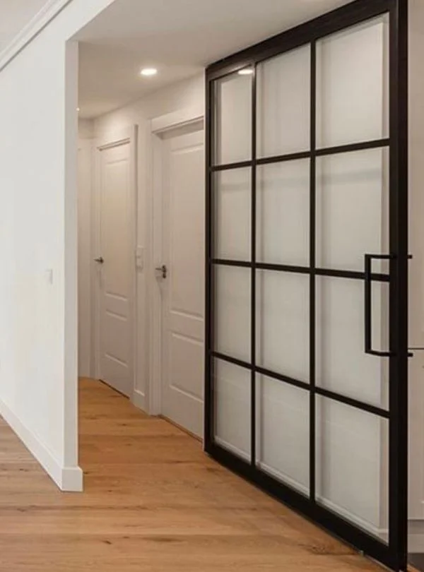 Puerta corredera de vidrio y metal negro instalada por Arte y Madera en Zaragoza, diseño contemporáneo