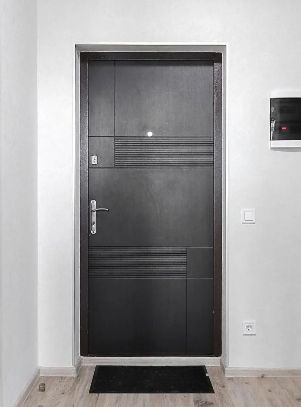 Puerta de entrada de madera oscura con diseño moderno instalada por Arte y Madera en Zaragoza